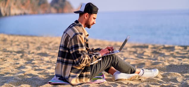 young man working on the beach with laptop